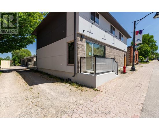 A modern house with a grey and white exterior and a brick pathway leading to the front door.