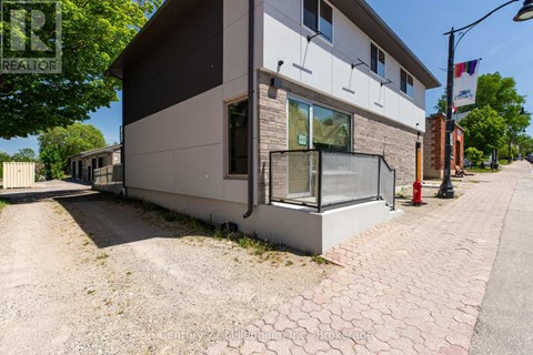 A modern house with a grey and white exterior and a brick pathway leading to the front door.