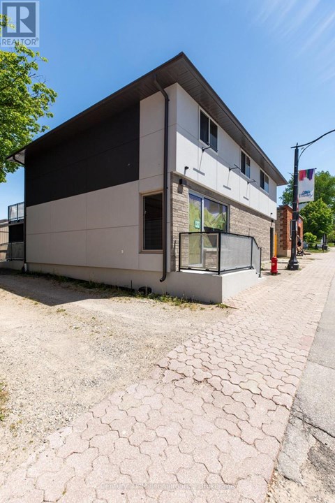 A modern building with a white and black facade is situated on a street with a paved sidewalk.