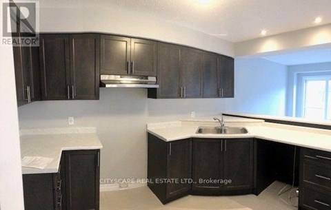 A kitchen with dark brown cabinets and a white countertop.