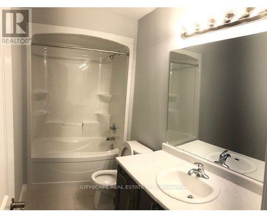 A white bathroom with a glass shower stall and a toilet.