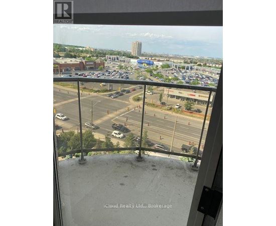 A view from a balcony looking out over a parking lot and buildings.