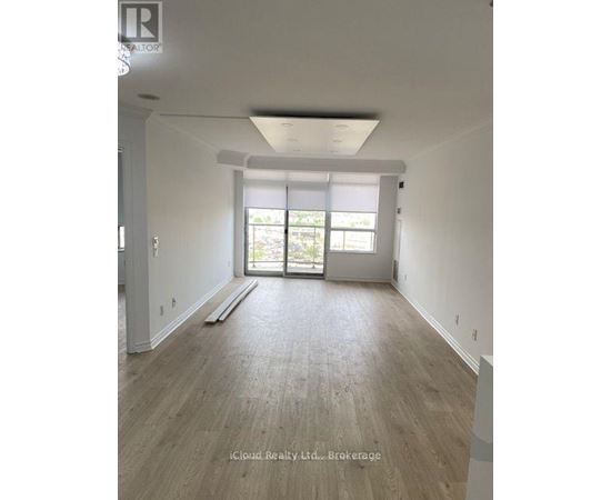 A spacious room with wooden flooring and a sliding glass door leading to a balcony.