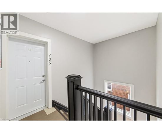 A room with a white door and a window with a black railing.