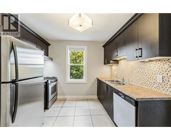 A kitchen with a refrigerator, oven, and sink.