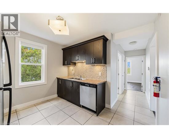 A kitchen with black cabinets and a white dishwasher.