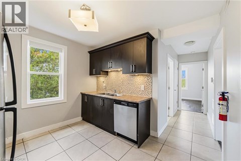 A kitchen with black cabinets and a white dishwasher.