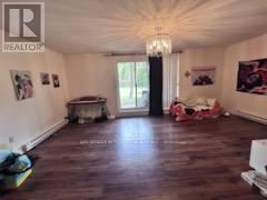 A large, empty room with wood flooring and a chandelier.