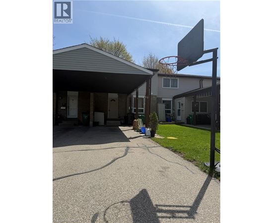 A basketball hoop is attached to a stand in the front yard of a house.