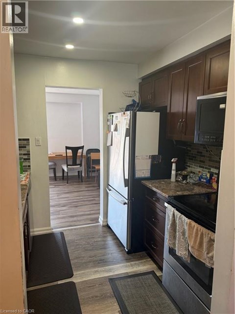 A kitchen with a black refrigerator and black oven.