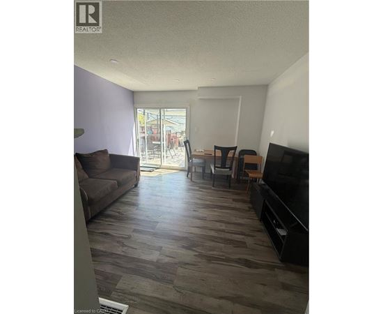 A living room with a couch, chairs, and a television.