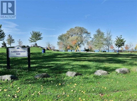 A sign for Claredon Beach Park stands in a grassy field.