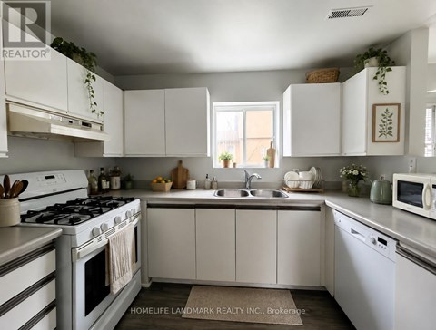 A white kitchen with a stove, sink, and cabinets.