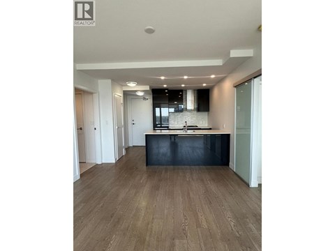 A spacious room with wooden flooring and a kitchen area with a counter and sink.
