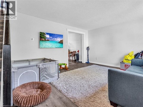 A living room with a grey couch, a white rug, and a painting of a beach scene on the wall.
