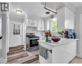 A kitchen with white cabinets and a wooden floor.