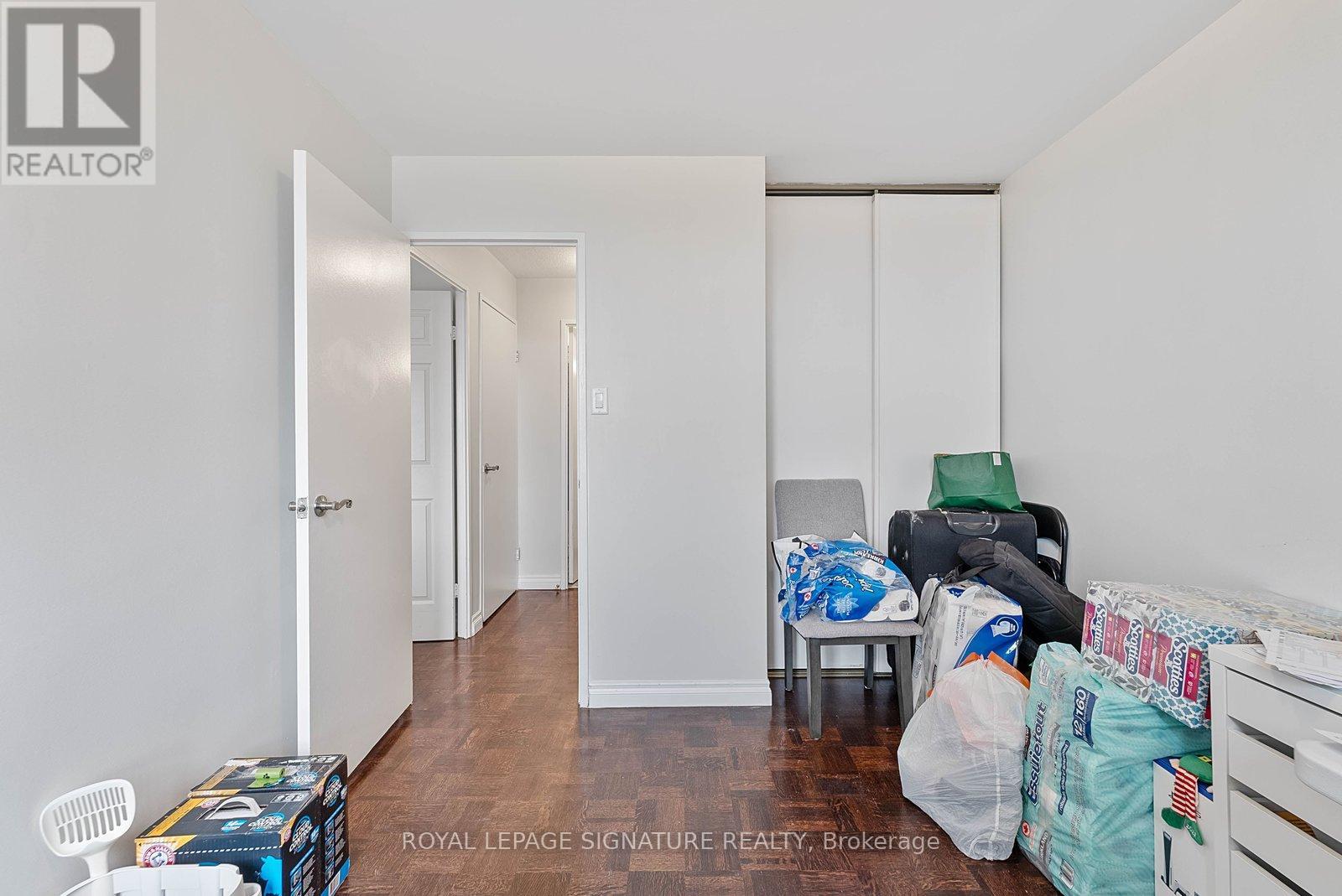 A room with white walls and wooden floors is filled with furniture and boxes.