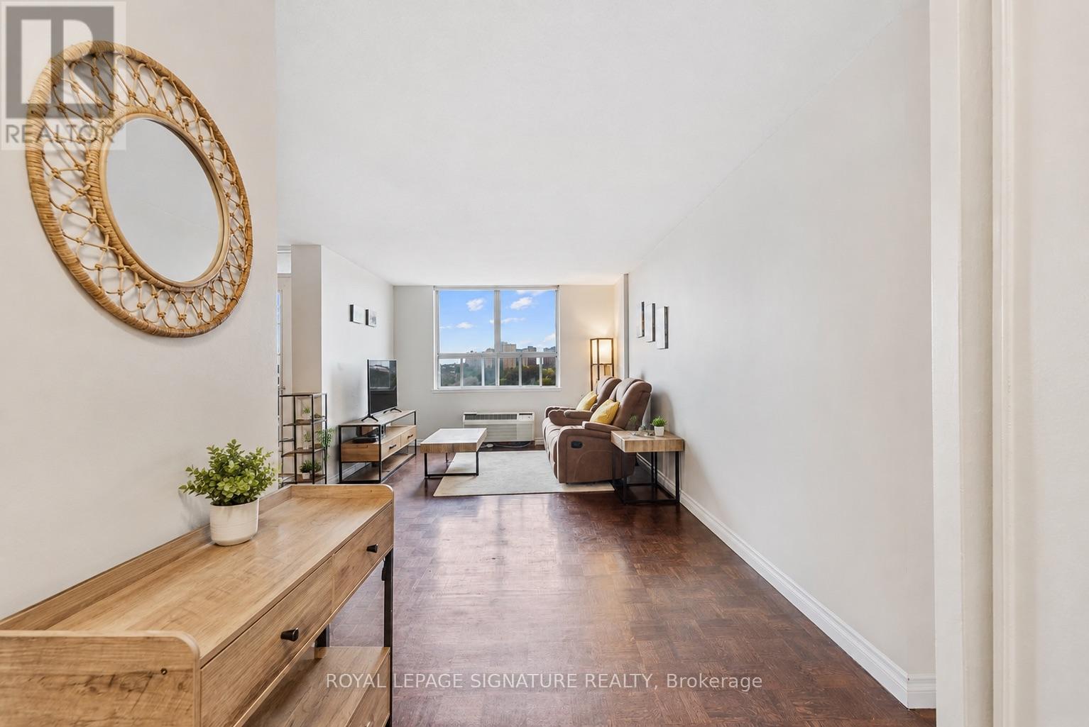A living room with a couch, a chair, a coffee table, and a mirror on the wall.