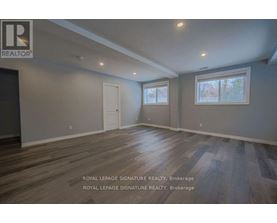 A room with wooden floors and two windows.
