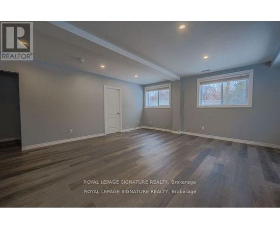 A room with wooden floors and two windows.
