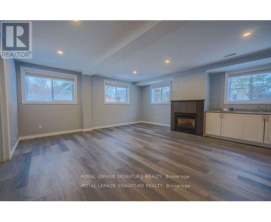 A spacious room with a fireplace and wooden flooring.