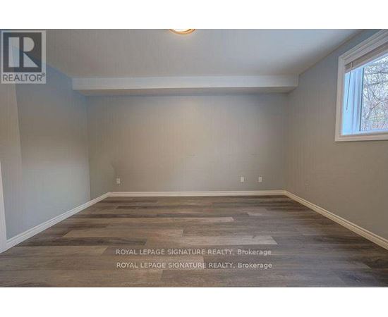 A room with wooden flooring and a window on the right side.