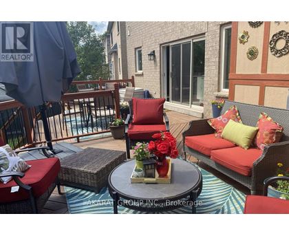 A patio with a table, chairs, and a vase of flowers.