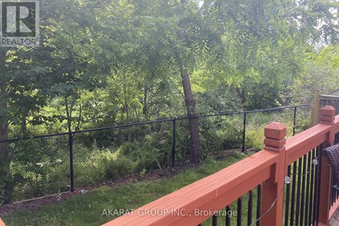 A wooden deck with a black fence and green trees in the background.