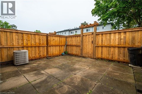 A backyard with a wooden fence and a tiled floor.