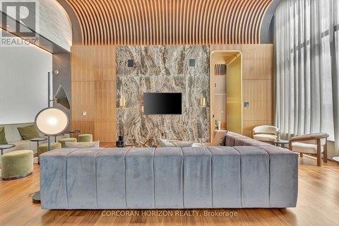 A modern living room with a grey sofa and a stone wall.
