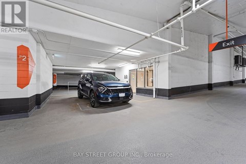 A car is parked in a garage with the sign "Exit" visible.