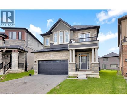 A large, two-story house with a garage is surrounded by a well-maintained lawn and other houses.