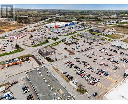 A parking lot with a large number of cars and a few buildings in the background.