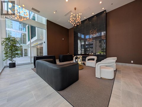 A modern living room with a black sofa and a glass wall.