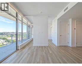A spacious room with wooden floors and large windows overlooking a cityscape.