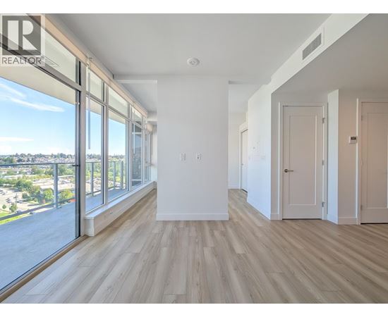 A spacious room with wooden floors and large windows overlooking a cityscape.