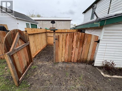 A wooden fence with a gate is in front of a house.