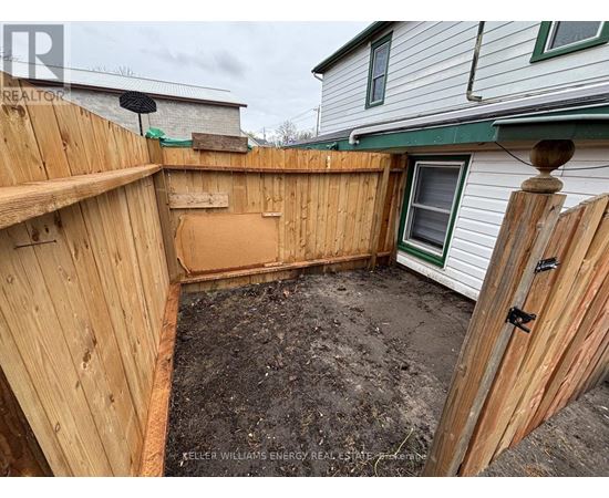 A backyard with a wooden fence and a dirt ground.