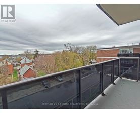 A balcony with a glass railing overlooking a residential area.