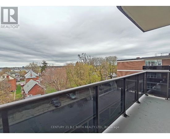 A balcony with a glass railing overlooking a residential area.