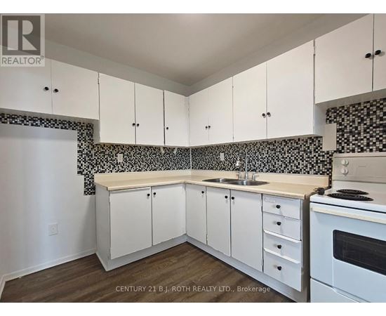 A kitchen with white cabinets and a black and white tiled backsplash.