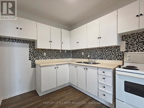 A kitchen with white cabinets and a black and white tiled backsplash.