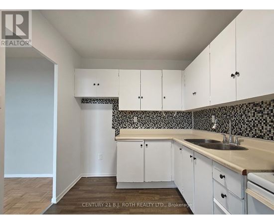 A kitchen with white cabinets and a black and white checkered backsplash.