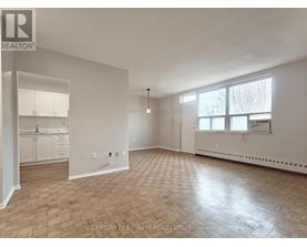 A spacious room with wooden flooring and white walls.