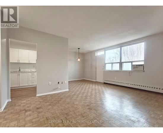 A spacious room with wooden flooring and white walls.