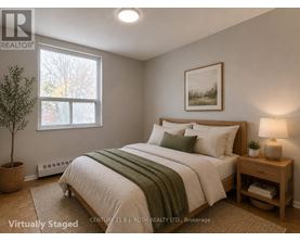 A bedroom with a bed, nightstand, and window.