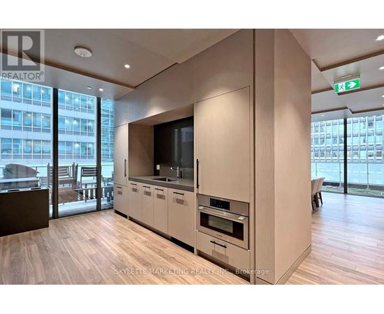 A modern kitchen with wooden floors and a large window.