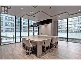 A conference room with a long table and chairs, a flat screen TV mounted on the wall, and a view of a cityscape through the windows.