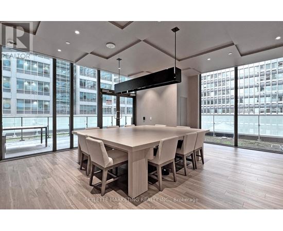 A conference room with a long table and chairs, a flat screen TV mounted on the wall, and a view of a cityscape through the windows.
