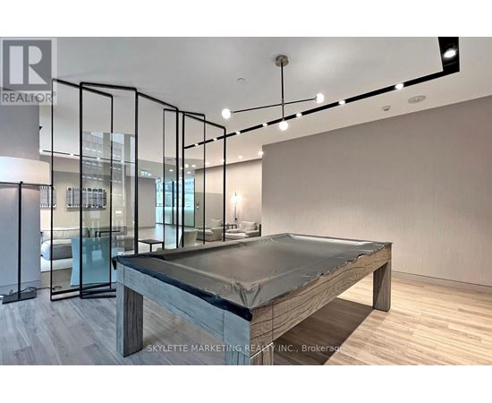 A modern bedroom with a glass partition wall and a bed with a grey mattress.